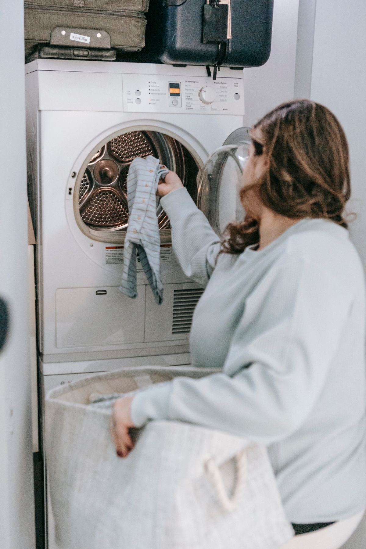 Homeowner handling clean laundry beside a modern appliance